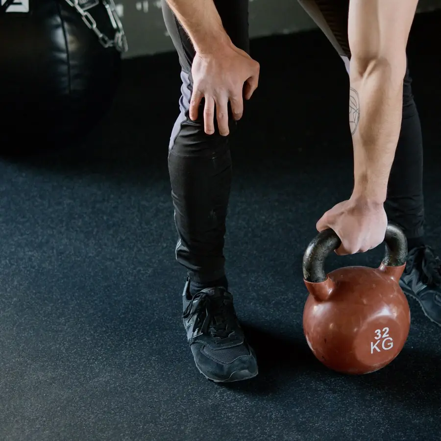 Hands gripping a kettlebell on a gym floor
