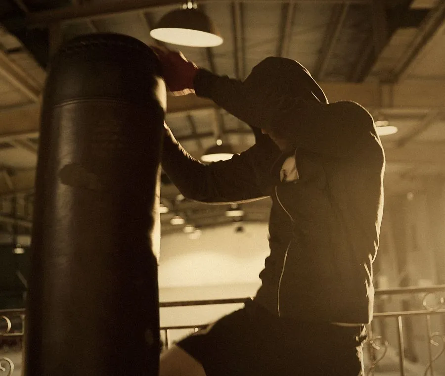 Kickboxing class in Dubai: a hooded boxer striking a heavy bag