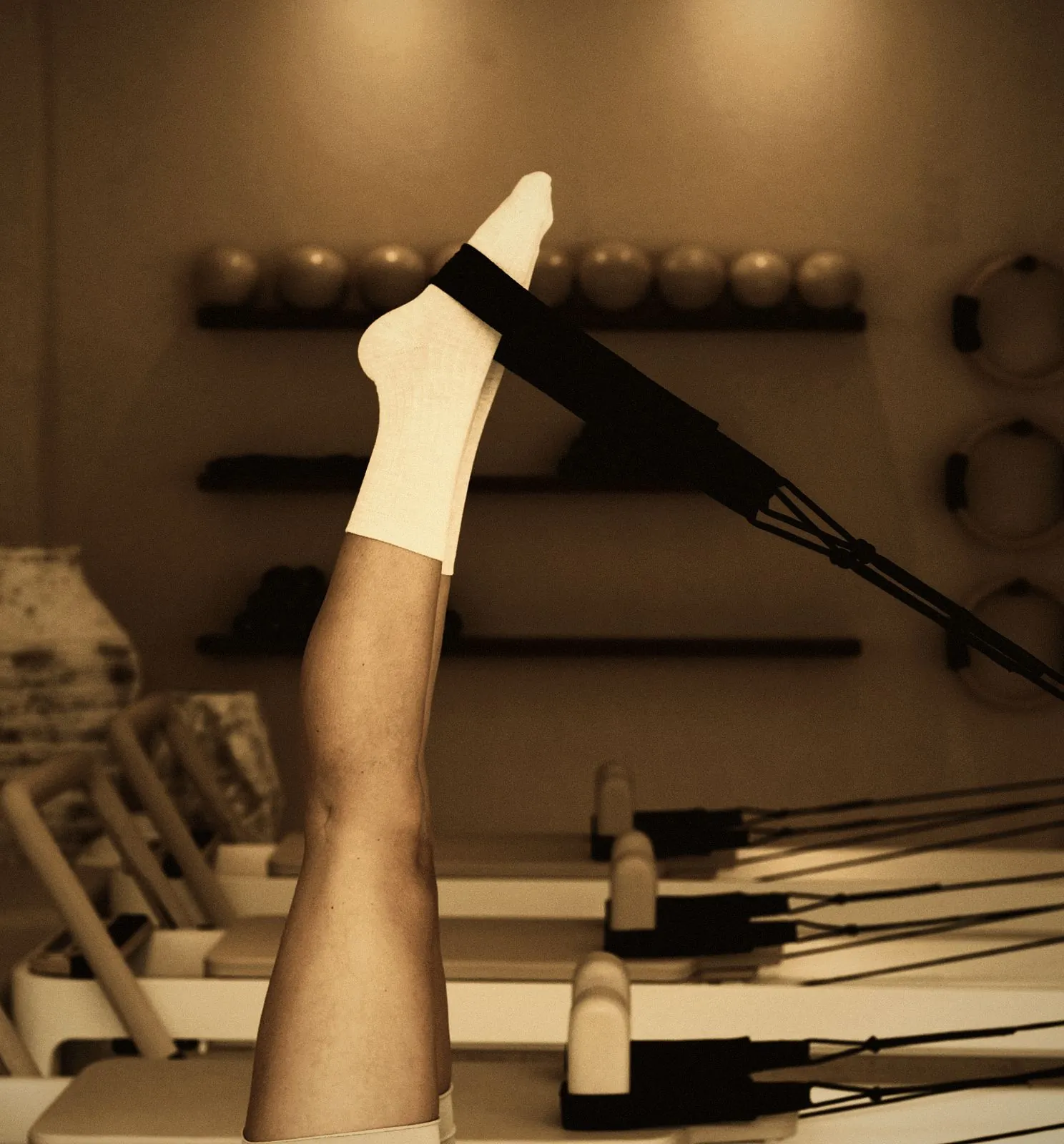 Legs in the foot straps of a Pilates reformer during a core workout